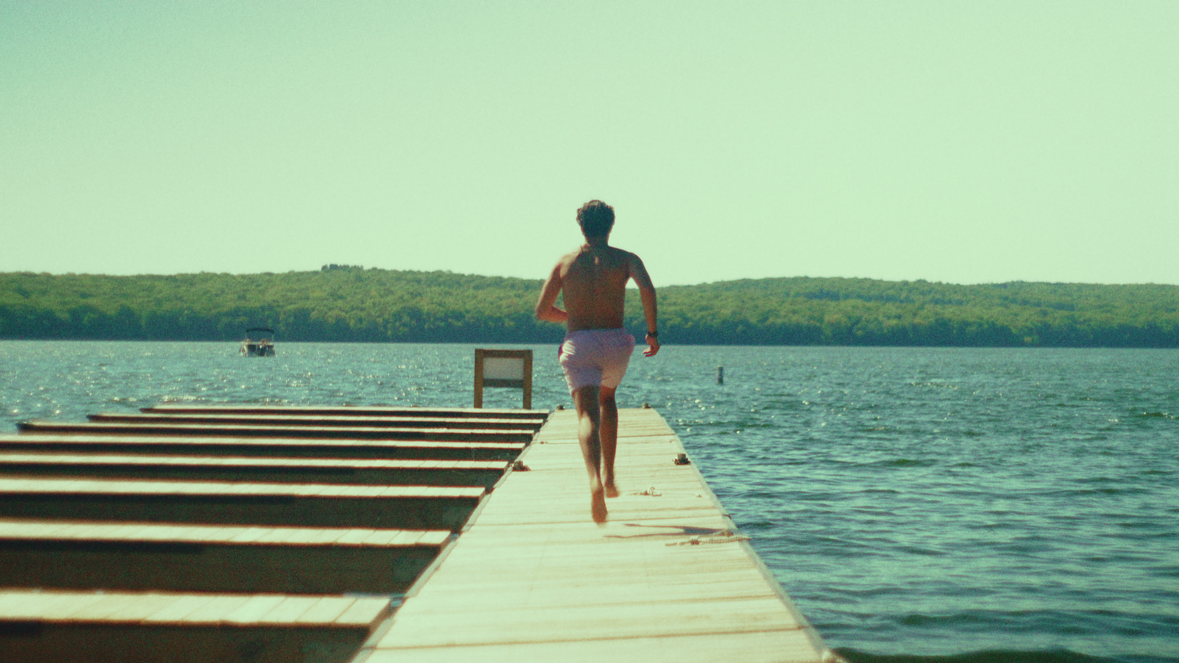 Jake running along a wooden dock toward the lake